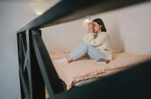 woman in white sweater and blue denim jeans sitting on bed