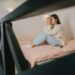 woman in white sweater and blue denim jeans sitting on bed